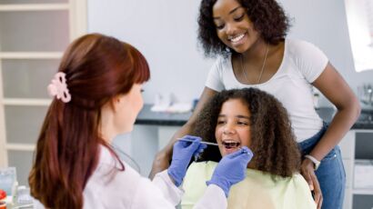 Pediatric dentistry — child dental exam with parent present in the clinic.