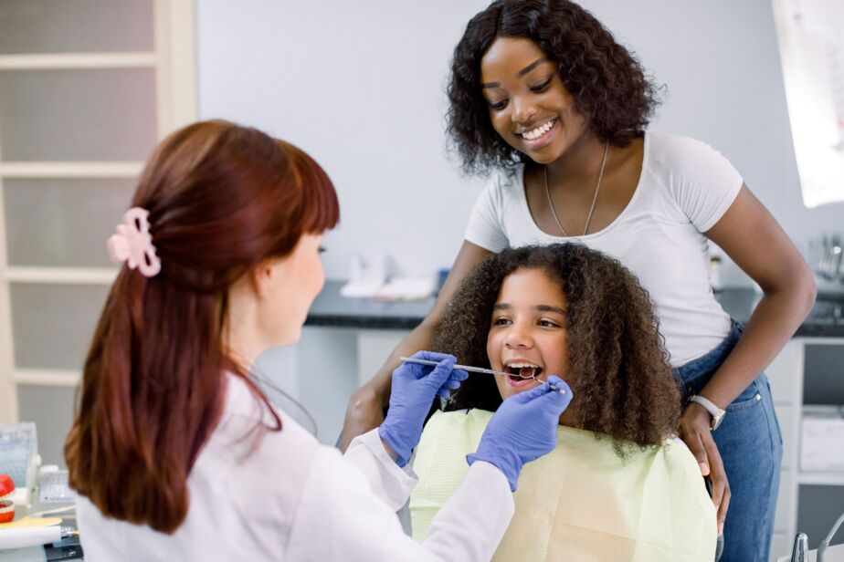 Pediatric dentistry — child dental exam with parent present in the clinic.