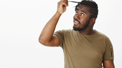 African man with braided hair examining his hair, afro hair transplant Turkey