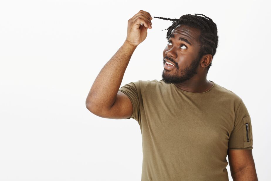 African man with braided hair examining his hair, afro hair transplant Turkey