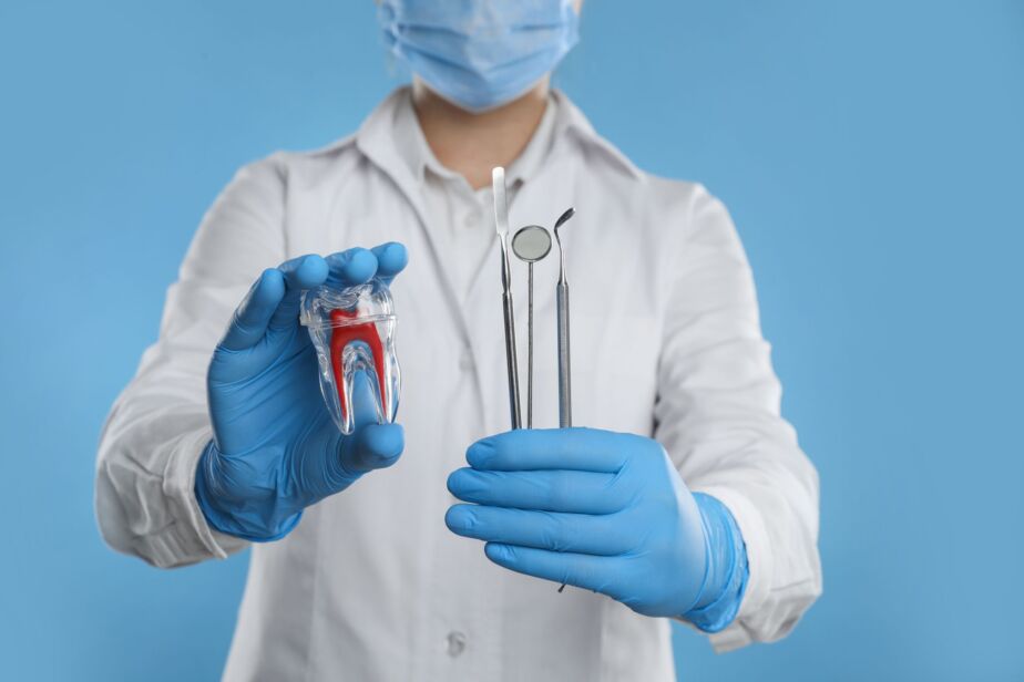 Dentist holding a tooth model and dental instruments to explain dental implant failure signs
