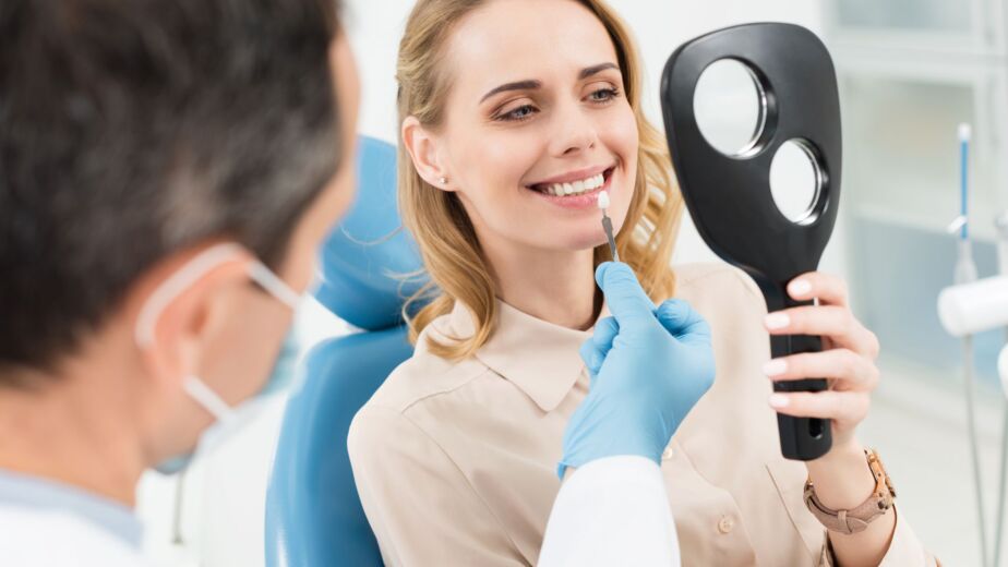 Hollywood smile consultation in Turkey: dentist assessing a patient’s smile in a hand mirror
