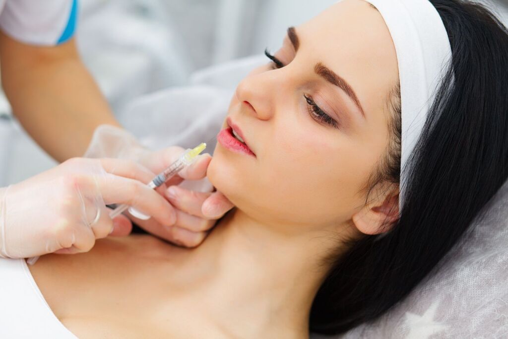 Clinician injecting dermal filler into the chin area to enhance facial contour and restore volume