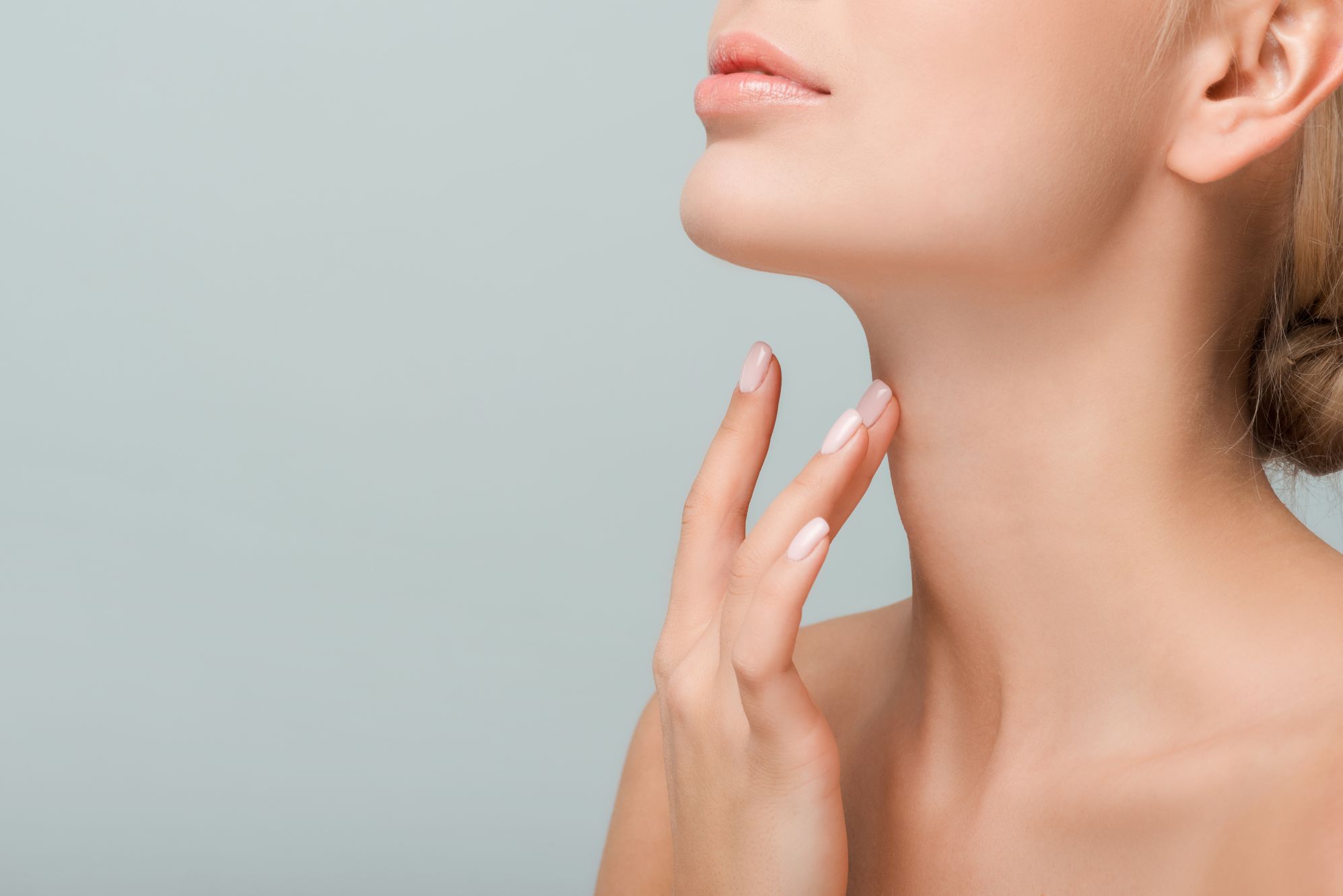 Woman touching smooth neck and jawline for neck lift in Turkey guide