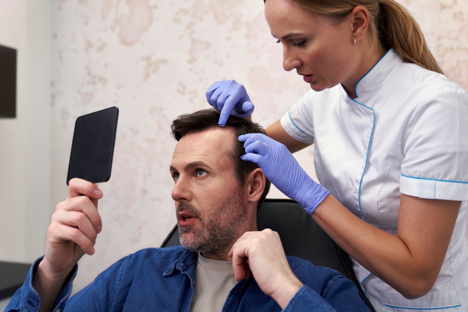 Hair transplant consultation with a specialist examining a man’s hairline while he looks in a mirror