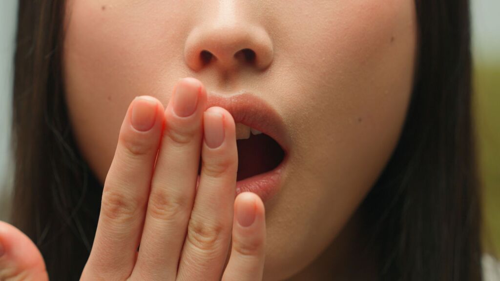 Woman covering her mouth to illustrate persistent bad breath